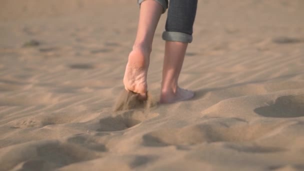 Primer plano, cámara lenta. Pies de mujer caminando sobre arena dorada en la playa
. - Metraje, vídeo