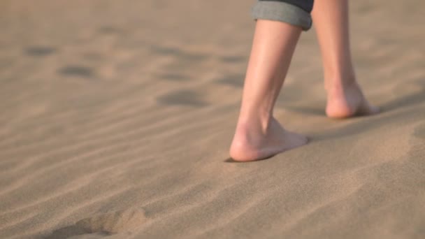 Chiudi, rallentatore. Donna piedi camminando sulla sabbia dorata in spiaggia
. - Filmati, video