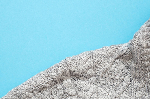 Parte de suéter de punto gris sobre fondo azul
 - Foto, Imagen