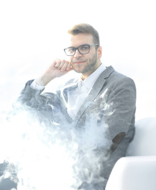 close up.pensive businessman with e-cigarette sitting in the break room - Fotó, kép