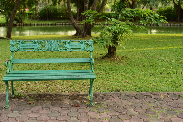 zielona ławka w pięknym parku. - Zdjęcie, obraz