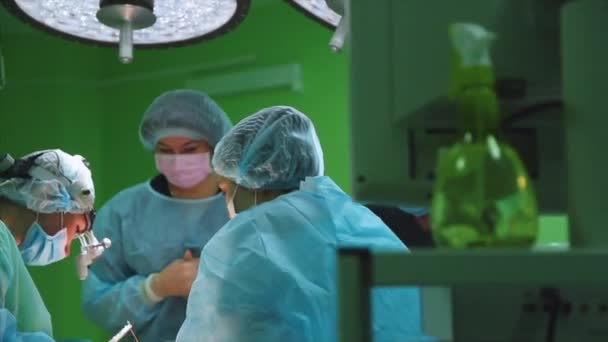 Noszenie odzieży ochronnej, wykonywania przy użyciu operacji Chirurdzy sterylizacji sprzętu. Zespół medyczny operacji chirurgicznych w jasne nowoczesnej sali operacyjnej - Materiał filmowy, wideo