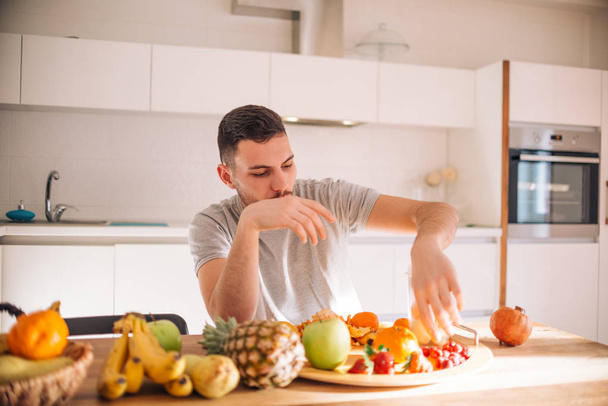 Nuori valkoihoinen mies valmistelee terveellistä smoothie aamulla
 - Valokuva, kuva