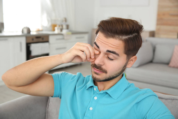 Young man rubbing eye at home. Annoying itch - Photo, Image