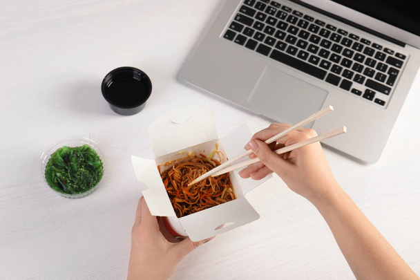 Woman eating tasty Chinese noodles at workplace, closeup. Food delivery - Foto, Imagen