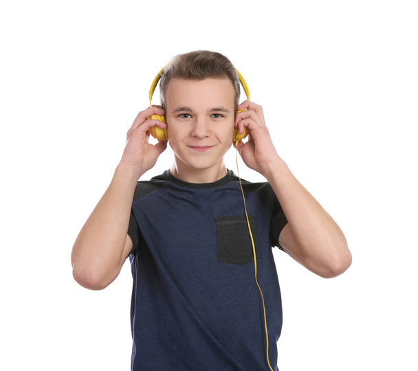 Teen boy listening to music with headphones on white background - Foto, afbeelding