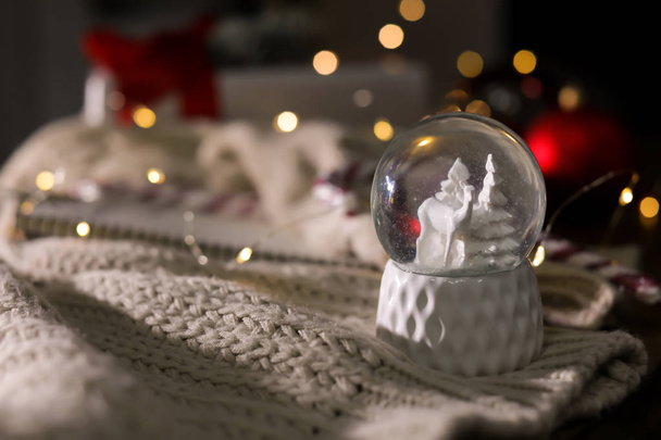 Sfera di neve di Natale con abiti a maglia su sfondo sfocato. Spazio per testo - Foto, immagini