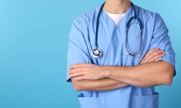 Jonge medische student in uniform op kleur achtergrond, close-up. Ruimte voor tekst - Foto, afbeelding