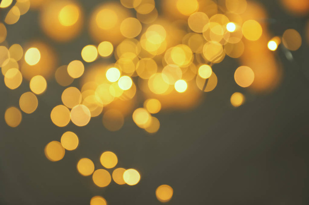 Blurred view of gold lights on dark background. Bokeh effect - Foto, afbeelding