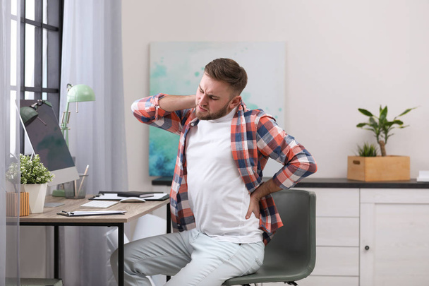 Young man suffering from back pain in office - Fotografie, Obrázek