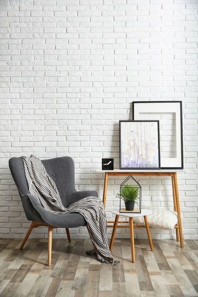Stylish living room interior with comfortable armchair near brick wall. Space for text - Valokuva, kuva