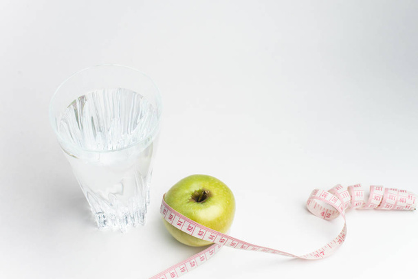 Lasi vettä, omena ja mittanauha eristetty valkoisella pohjalla
 - Valokuva, kuva