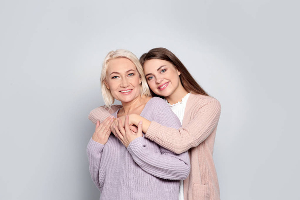 Portrait of mature woman and her daughter on color background - Photo, Image