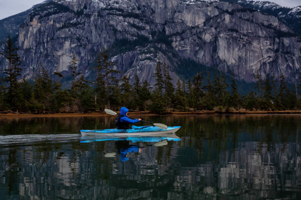 Adventurous man kayaking in peaceful water during a cloudy winter sunset. Taken in Squamish, North of Vancouver, BC, Canada. - Foto, Imagen