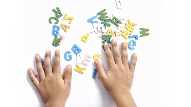 Kid's hand playing with colorful alphabets - Фото, изображение