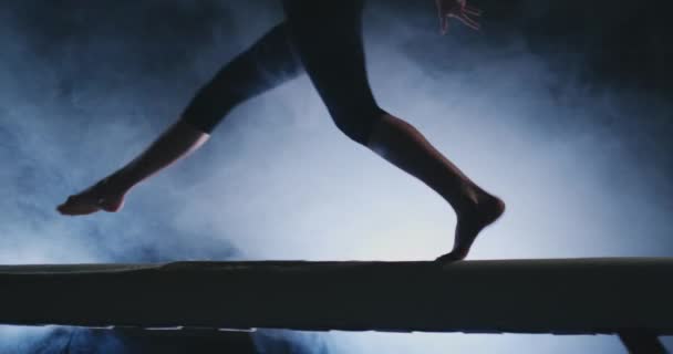 Piernas Chica profesional gimnastas saltar en cámara lenta en el humo en la viga de equilibrio. Gimnasia artística para mujer
 - Imágenes, Vídeo