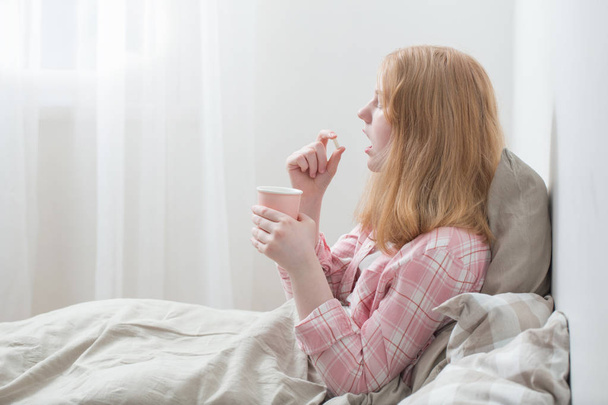 girl takes  pill in bedroom - Foto, Imagem