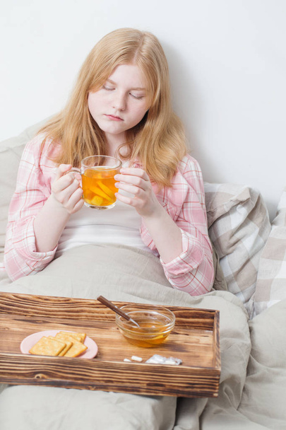 sick girl with  cup of tea with lemon and ginger - 写真・画像