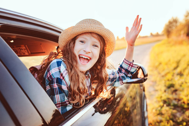 enfant heureux fille regardant par la fenêtre de la voiture pendant le voyage sur la route pendant les vacances d'été. L'été, à la découverte de nouveaux lieux concept - Photo, image