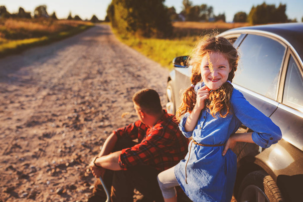 pai e filha trocando pneu quebrado durante a viagem de verão rural. Criança ajudando a corrigir problemas com o carro
 - Foto, Imagem