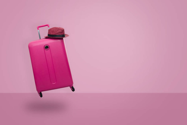 Pink suitcase with hat  on pastel pink background. travel concep - Foto, immagini