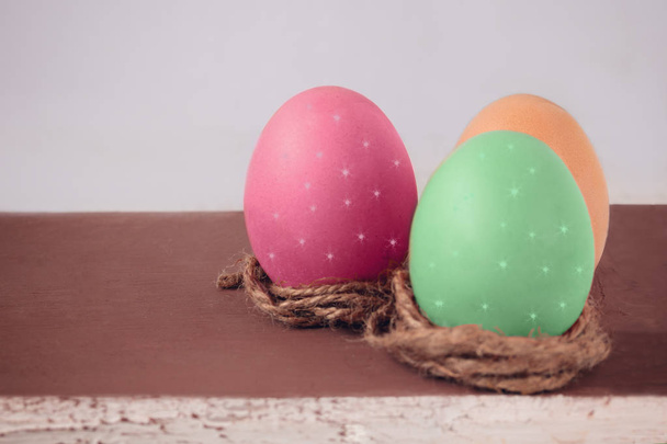 Zielony, czerwony i żółty jajko na brązowy deska drewniany. Symbolem Wielkanocy - Zdjęcie, obraz