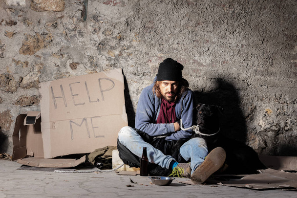 Homeless man sitting on the street with a dog - Foto, imagen