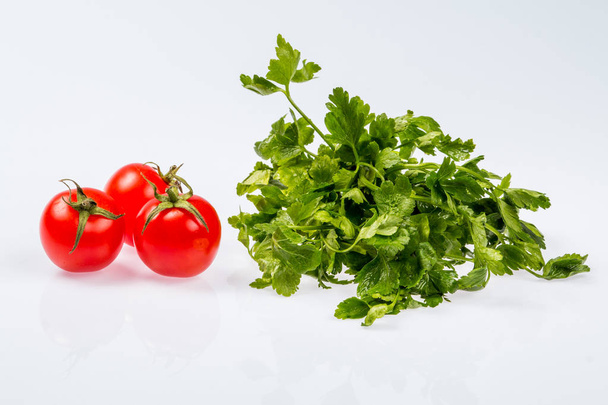 bouquet vert frais mûr de persil avec trois tomates, ingrédient brillant sur fond blanc
 - Photo, image