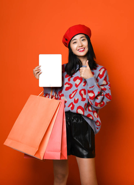 Young asian woman with shopping bags on color background - Foto, Bild