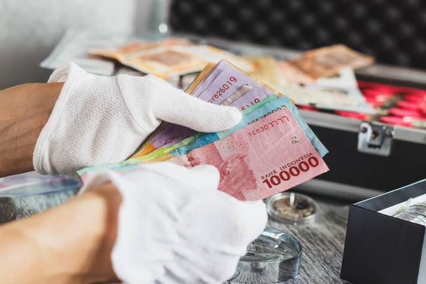 Hands in the white gloves hold different banknotes - Photo, Image