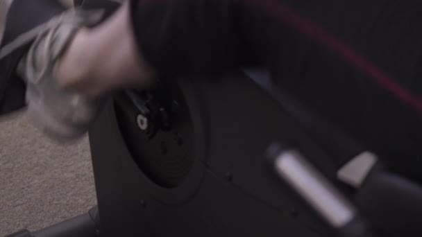 Panning tilting shot of a woman using a stationary bike at the gym. - Felvétel, videó