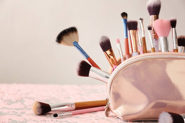 Набор кистей для макияжа в косметической сумке на столе
 - Фото, изображение
