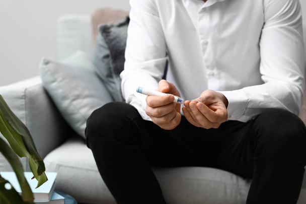 Діабетичний чоловік бере зразки крові з ланцетною ручкою вдома
 - Фото, зображення