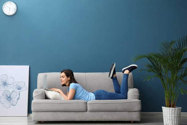Krásná mladá žena s laptopem ležící na pohovce doma - Fotografie, Obrázek
