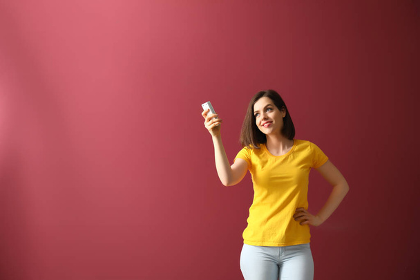 Young woman with air conditioner remote control on color background - Foto, immagini