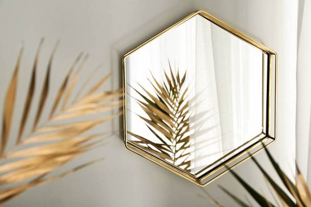 Spiegel und goldene tropische Blätter im Zimmer - Foto, Bild