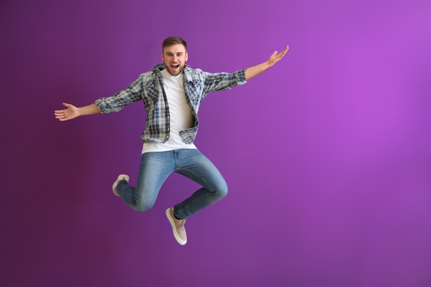 Jumping young man on color background - Fotó, kép