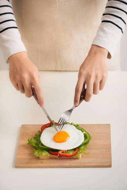 Ember kezében vágjuk a tojásokat, a vágódeszka, kenyér, h tálalva - Fotó, kép