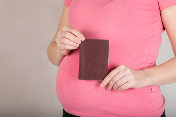 Young pregnant woman keeps her travel pass. Closeup - Photo, Image