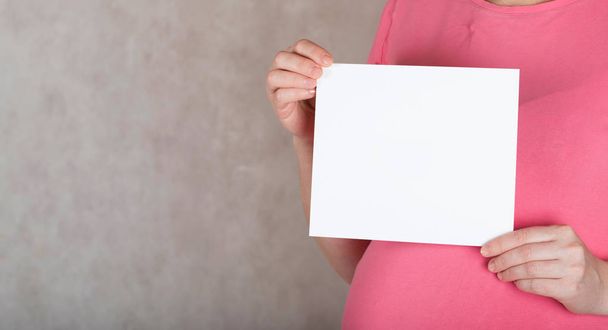 Young έγκυος μεταξύ 30 και 35 χρονών γυναίκα κρατά ένα κενό  - Φωτογραφία, εικόνα