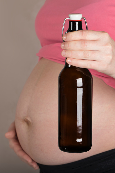 Joven embarazada mantiene botella de vidrio de cerveza cerca de su bel
 - Foto, Imagen