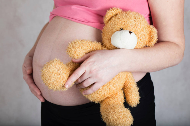 Fiatal terhes nő tartja barna plüss mackó.  - Fotó, kép