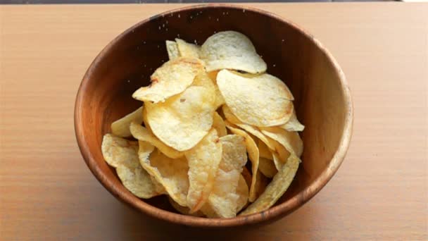 Sprinkle salt on a pile of potato chips in a wooden bowl in Slow Motion - Metraje, vídeo
