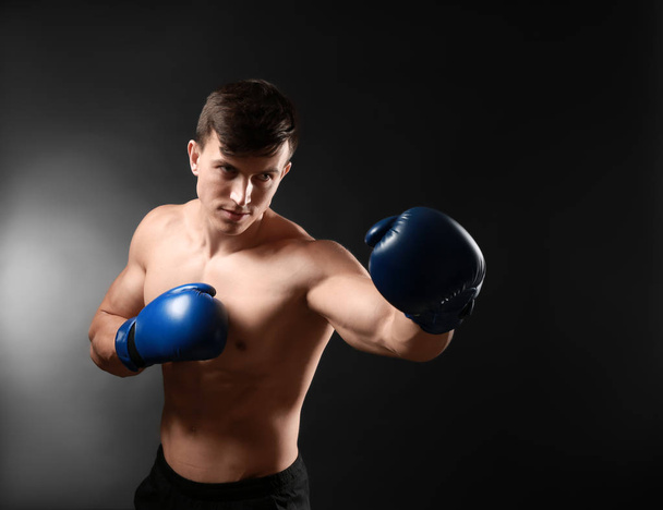 Houkutteleva nuori nyrkkeilijä tummalla taustalla
 - Valokuva, kuva