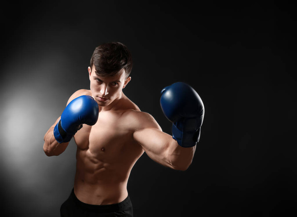 Attractive young boxer on dark background - Фото, изображение