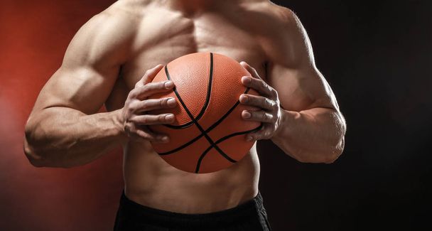 Muscular bodybuilder with ball on dark background - Photo, Image