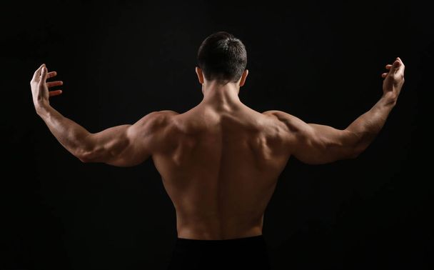 Muscular bodybuilder on dark background, back view - Foto, Bild