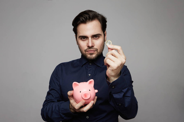Man putting coin in piggy bank. Saving money concept. - Фото, изображение