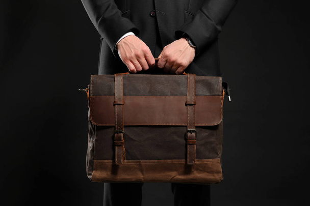 Handsome businessman with stylish briefcase on dark background - Foto, afbeelding