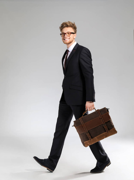 Going businessman with stylish briefcase on light background - Fotoğraf, Görsel